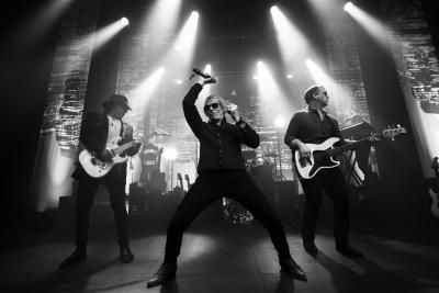 Black and white image of The Bon Jovi Experience with musicians playing guitar on stage.